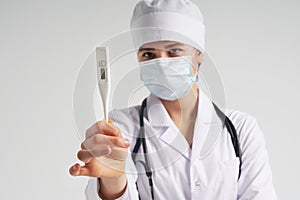 Young female doctor showing thermometer over white background, studio shot