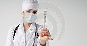 Young female doctor showing thermometer over white background, studio shot