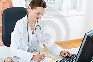 Doctor at desk in clinic writing a file or dossier photo