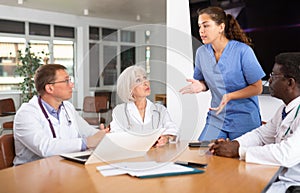 Young female doctor speaks at meeting of colleagues and tells reports on condition of patients