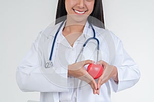 Young female doctor with stethoscope holding a heart on isolated white background. Concept of Cardiology healthcare and medical by