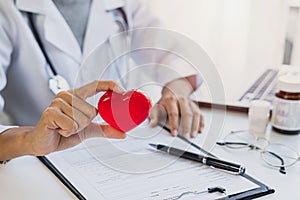 Young female doctor with the stethoscope holding red heart