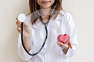 Young female doctor with the stethoscope holding red heart, cardiolog healthy care