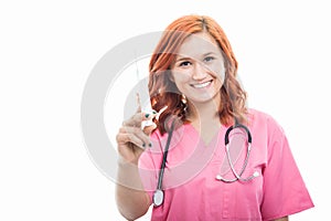 Young female doctor with stethoscope holding syringe