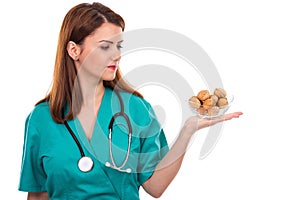 Young female doctor with stethoscope holding walnuts