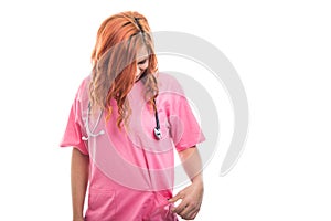 Young female doctor with stethoscope looking into his poket