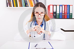 Young female doctor in uniform in doctor`s ofice writting a document