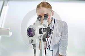 Young female doctor using colposcope at work