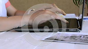 Young female doctor in a white coat working on laptop in hospital office room, therapist typing on computer consult patient online