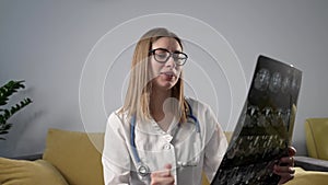 Young female doctor in white uniform talking to camera