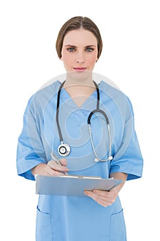 Young female doctor working with her clipboard and looking into the camera