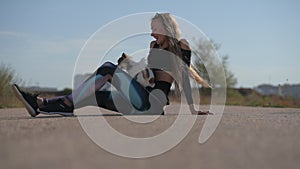 young female dog owner trainer teching pet chihuahua to make tricks sitting on asphalt of road empty street during