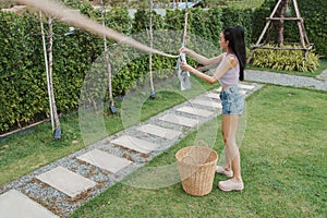 Young female doing laundry in bright home garden