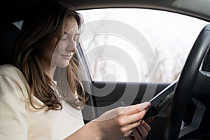 Young female driver holds a map in her hands and chooses the direction for the trip. Navigating the terrain with a paper