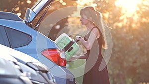 Young female driver loading luggage suitcase bag inside her car. Travelling and vacations concept