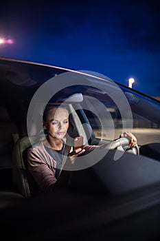 Young female driver playing with her cellphone instead of paying attention to driving