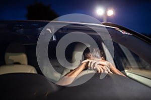 Young female driver at the wheel of her car, super tired