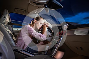 Young female driver at the wheel of her car, super tired