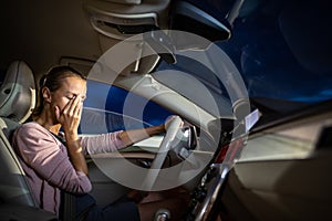 Young female driver at the wheel of her car, super tired