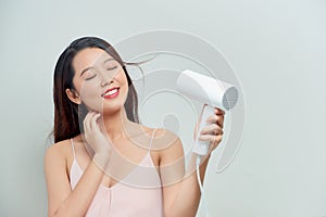 Young female drying her beautiful hair with hairdryer