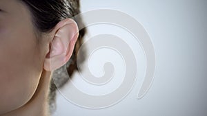 Young female ear closeup, useless rumors and disinformation, privacy intrusion