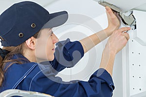 young female electrician installing electrical socket on wall with screwdriver