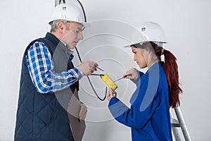 Young female electrician with mentor