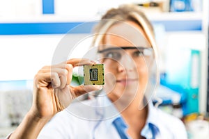 Young female electronic engineer holding CPU in hand
