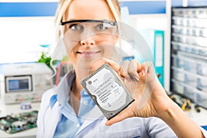 Young female electronic engineer holding HDD in hand