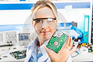 Young female electronic engineer holding HDD in hand