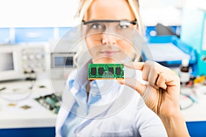 Young female electronic engineer holding memory module in hand