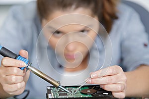 Young female electronic engineer soldering computer motherboard in laboratory