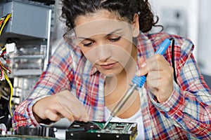 Young female electronic engineer soldering computer parts