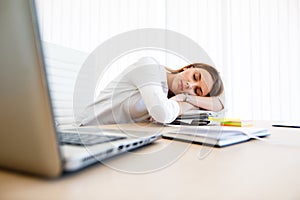 Young female employee sleeps at workplace
