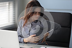 Young female employee suffer from lower backache in office