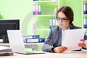 The young female employee very busy with ongoing paperwork