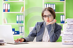 The young female employee very busy with ongoing paperwork