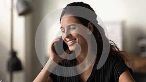 Young female engaged in phone talk holding cell at ear