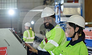 Young female engineer learning to run machinery at a factory with veteran engineers