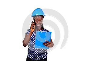Young female engineer reading notes on clipboard and talking on mobile phone