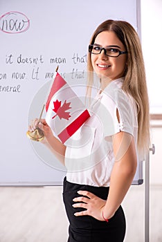 The young female english language teacher standing in front of the blackboard