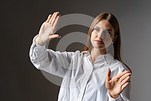 Young female entrepreneur touching virtual screen against grey studio background