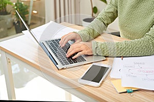 Young female entrepreneur working sitting at a desk typing on her laptop in a home office