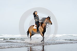 young female equestrian riding horse in wavy water