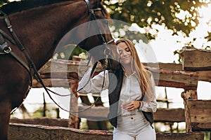 A young female equestrian stands near her horse and prepares for a competition.