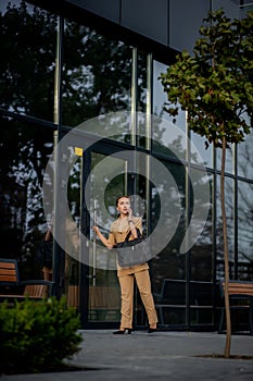 Young female executive standing outside office building talking on cell phone. Caucacian businesswoman making a phone call while