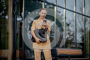 Young female executive standing outside office building talking on cell phone. Caucacian businesswoman making a phone call while