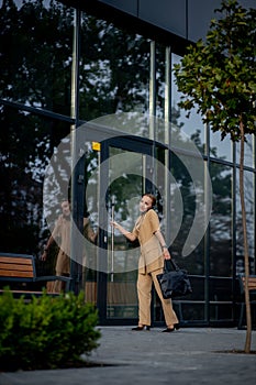 Young female executive standing outside office building talking on cell phone. Caucacian businesswoman making a phone call while