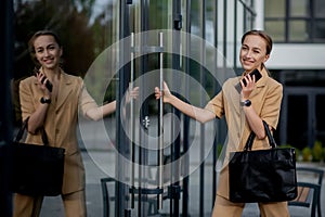 Young female executive standing outside office building talking on cell phone. Caucacian businesswoman making a phone call while