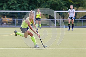 Young female field hockey player leading ball in attack.